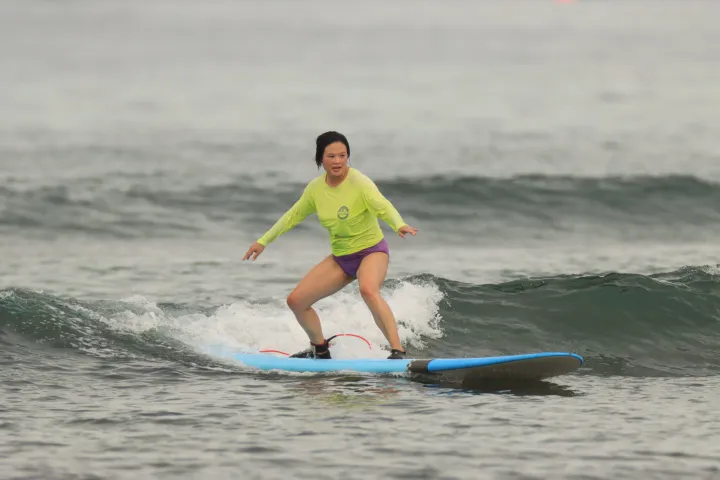 a young girl riding a wave on a surfboard in the ocean