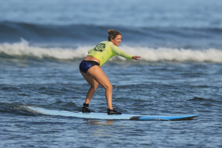 a young girl riding a wave on a surfboard in the water