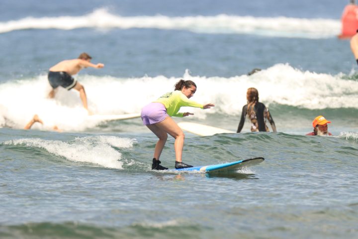 a young girl riding a wave on a surfboard in the ocean